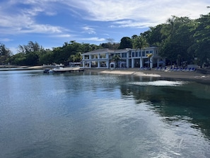 Ein Hotel am Wasser mit einer Anlegestelle, Liegestühlen und freiem Blick auf das Wasser.