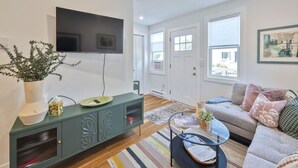Ein Wohnzimmer mit Flachbildfernseher, einem grünen Schrank, einer Couch und einem Couchtisch.