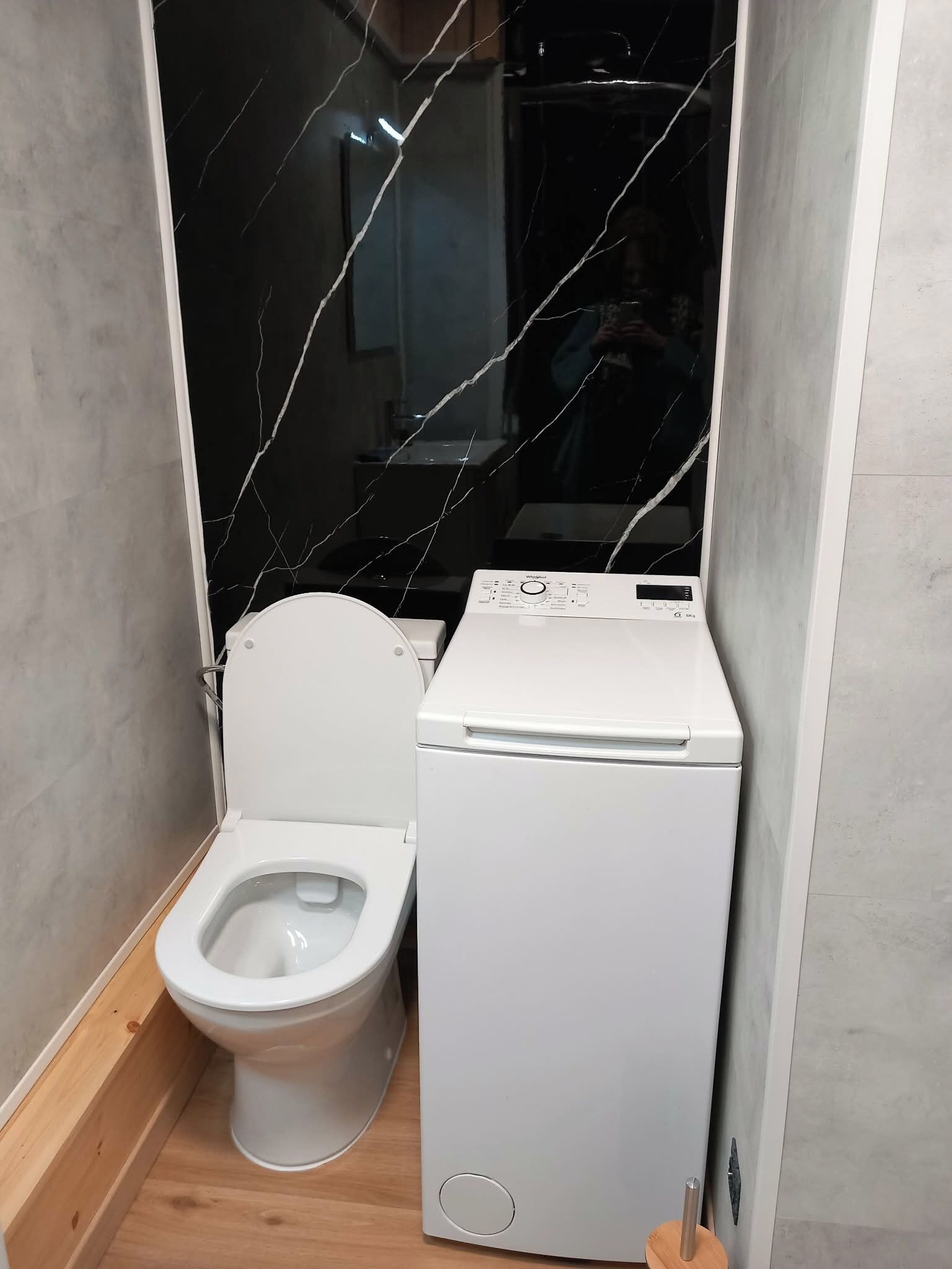 A compact bathroom with a white toilet and a white washing machine.