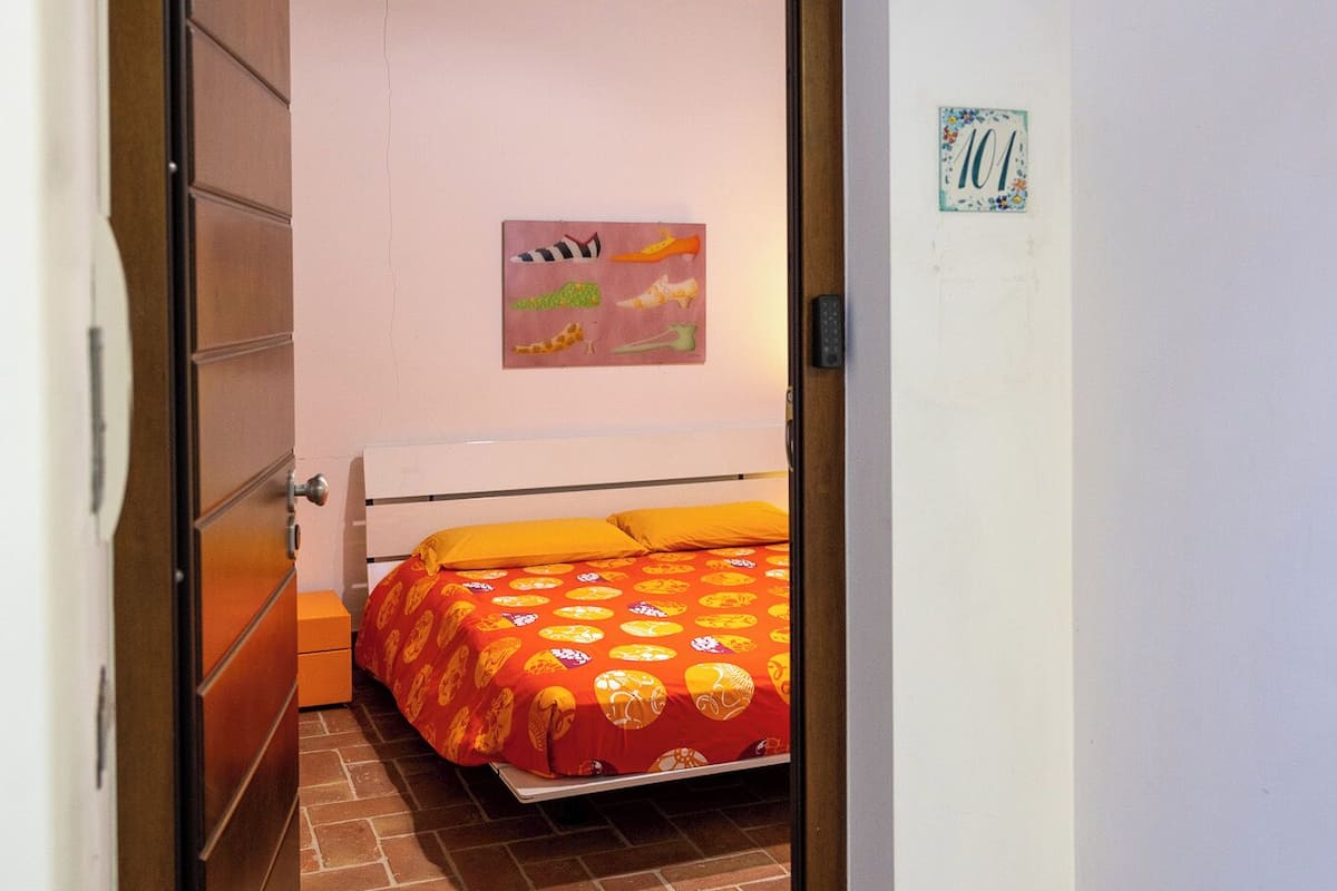 Quarto com uma cama, uma porta e uma parede com sinal de número.