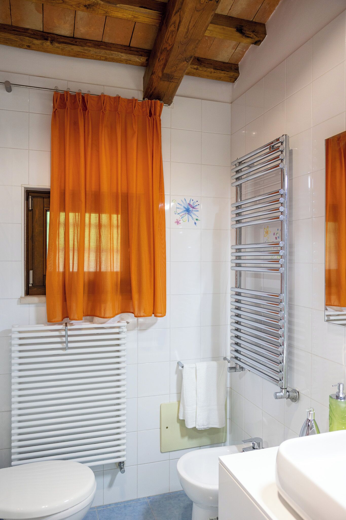 A bathroom with a white toilet, a bidet, a white sink, and a towel rack.