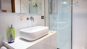 A modern bathroom with a white sink, a glass shower enclosure, and decorative floral tiles. - Lilum B&B Villa Patrizia - Mamo Florence (Itri)