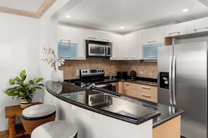 Eine moderne Küche mit eingebauter Mikrowelle, einem Edelstahl-Kühlschrank und einer Arbeitsplatte aus Granit.