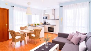 A modern apartment with a dining area, kitchen, and living room. - Casa Almeida en Conil (Conil de la frontera)