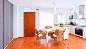 A modern kitchen with a dining area, a wooden door, and a tiled floor. - Casa Almeida en Conil (Conil de la frontera)