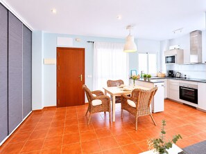 Eine moderne Küche mit Essbereich, einer Holztür und einem gefliesten Boden.