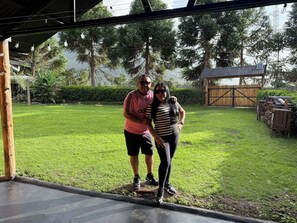 Un espacio al aire libre cubierto con césped, estructuras de madera y árboles al fondo.