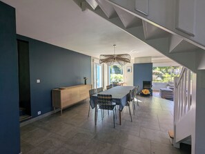 Un comedor moderno con una mesa, sillas, un banco de madera y una lámpara colgante.
