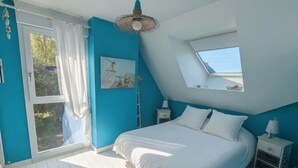 Una camera da letto con un velux, un letto, un comodino e vista sull'esterno.