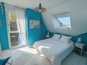 Un dormitorio con tragaluz, cama, mesita de noche y vistas al exterior.