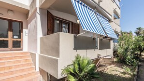 A building with a balcony, a wooden door, and a small garden area. - Casa AzzurroLido (Alghero)