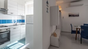 A modern kitchen with white cabinets, a built-in oven, and a blue-tiled backsplash. - Casa AzzurroLido (Alghero)
