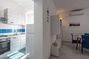 A modern kitchen with white cabinets, a built-in oven, and a blue-tiled backsplash. - Casa AzzurroLido (Alghero)
