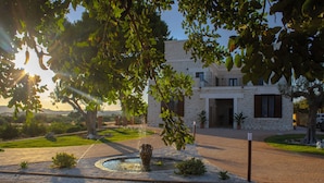 Un edificio de piedra con patio, una fuente y vegetación circundante.