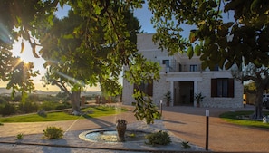 A stone building with a courtyard, a fountain, and surrounding greenery.