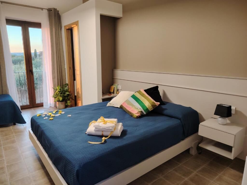 Un dormitorio con cama, mesita de noche y vistas al exterior.