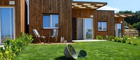 A modern wooden building with large windows, a covered outdoor seating area, and a well-maintained lawn.
