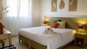 Una cama bien hecha con cabecera, dos lámparas de noche y un cojín decorativo.