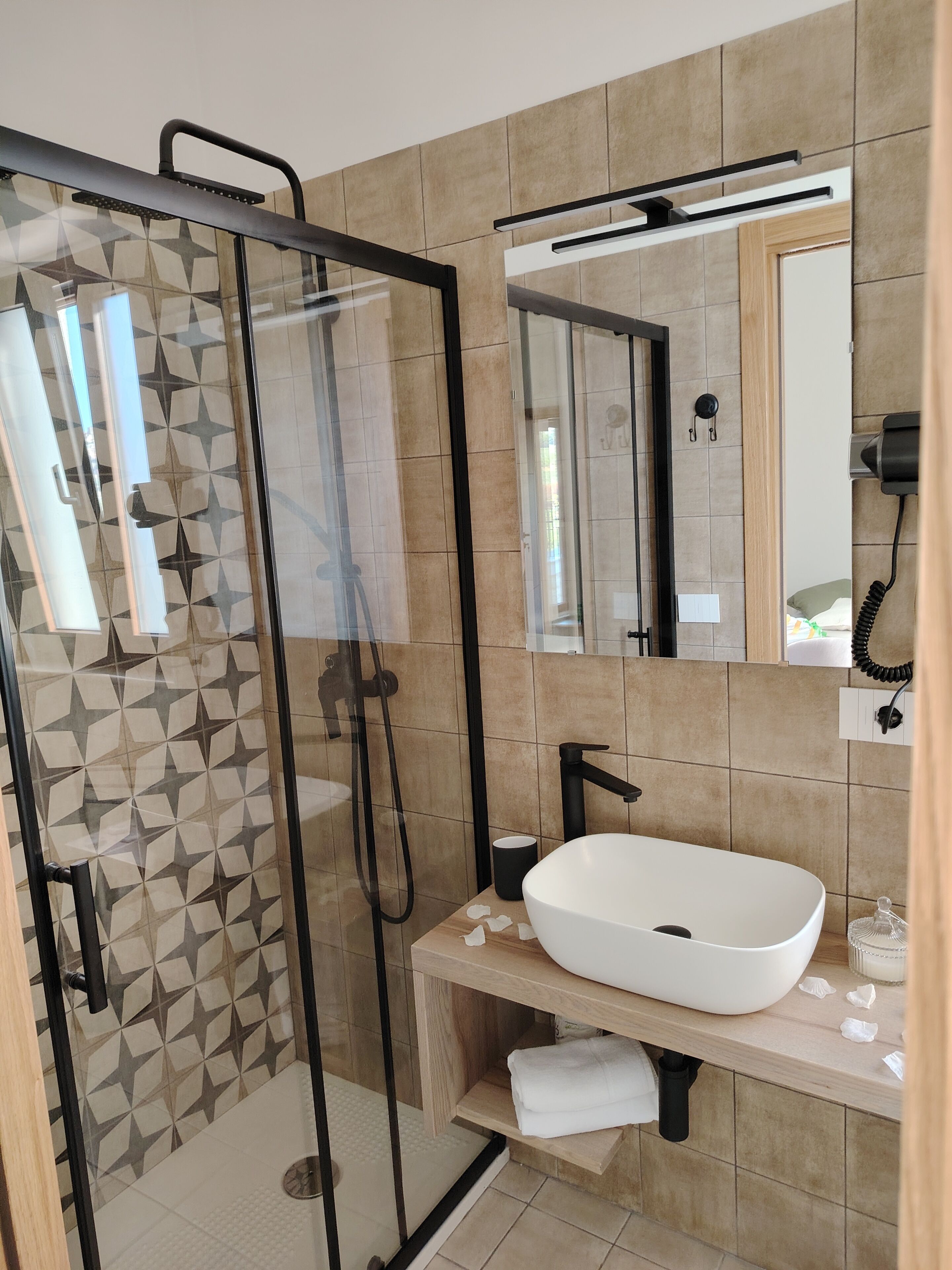 A modern bathroom with a glass-enclosed shower, a white sink, and a mirror above the sink.