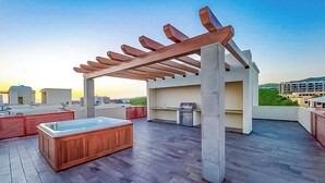 Een terras op het dak met een hottub, een houten pergola en uitzicht over de stad.