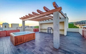 A rooftop terrace with a hot tub, wooden pergola, and a view of the city. - Private Terrace with Views, Pool & Gym Access (Cabo San Lucas)