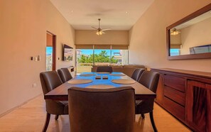 A dining area with a long table, chairs, and a ceiling fan. - Private Terrace with Views, Pool & Gym Access (Cabo San Lucas)