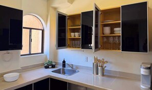 Eine moderne Küche mit integriertem Spülbecken, einem Fenster und offenen Schränken voller Geschirr und Gläser.