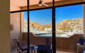 Ein Balkon mit Blick auf eine Marina, ein Stuhl, ein Tisch und ein Blumentopf.