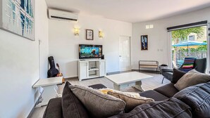 Een woonkamer met een televisie, een gitaar, een bank en een salontafel.