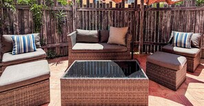 A patio area with wicker furniture, including a sofa and ottomans, and a glass-top coffee table. - Ground Floor Condo with Pool, Near Cerritos Beach (El Pescadero)