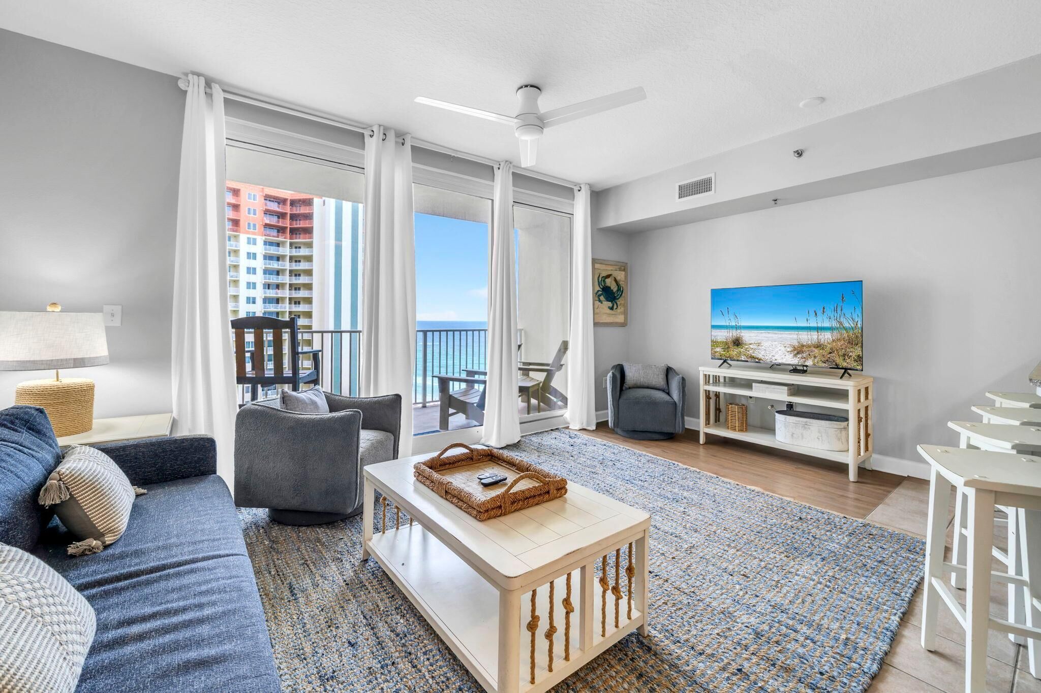 Una sala de estar moderna con un sofá, una mesa de centro, un televisor y un balcón con vistas a edificios altos.