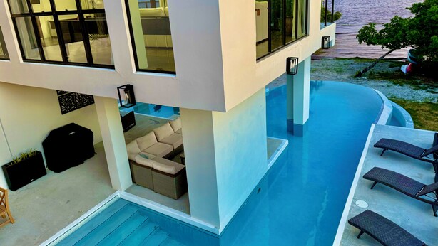 Una casa moderna con un'ampia vetrata, una piscina e vista mare.
