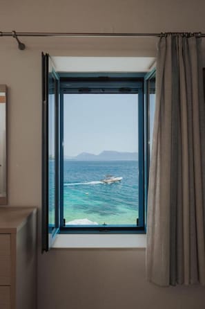 A room with a window overlooking the sea, a curtain, and a wooden cabinet. - Apartment with Balcony - Sea Mansion Lefkada (Lefkada)
