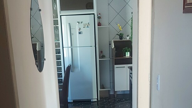 Un pasillo con alfombra azul, un refrigerador y una zona de cocina con gabinetes y un lavamanos.