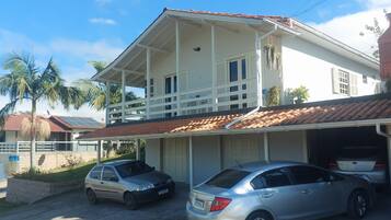 Une maison à deux étages avec un porche couvert, un garage pouvant accueillir deux voitures et un toit recouvert de tuiles rouges.