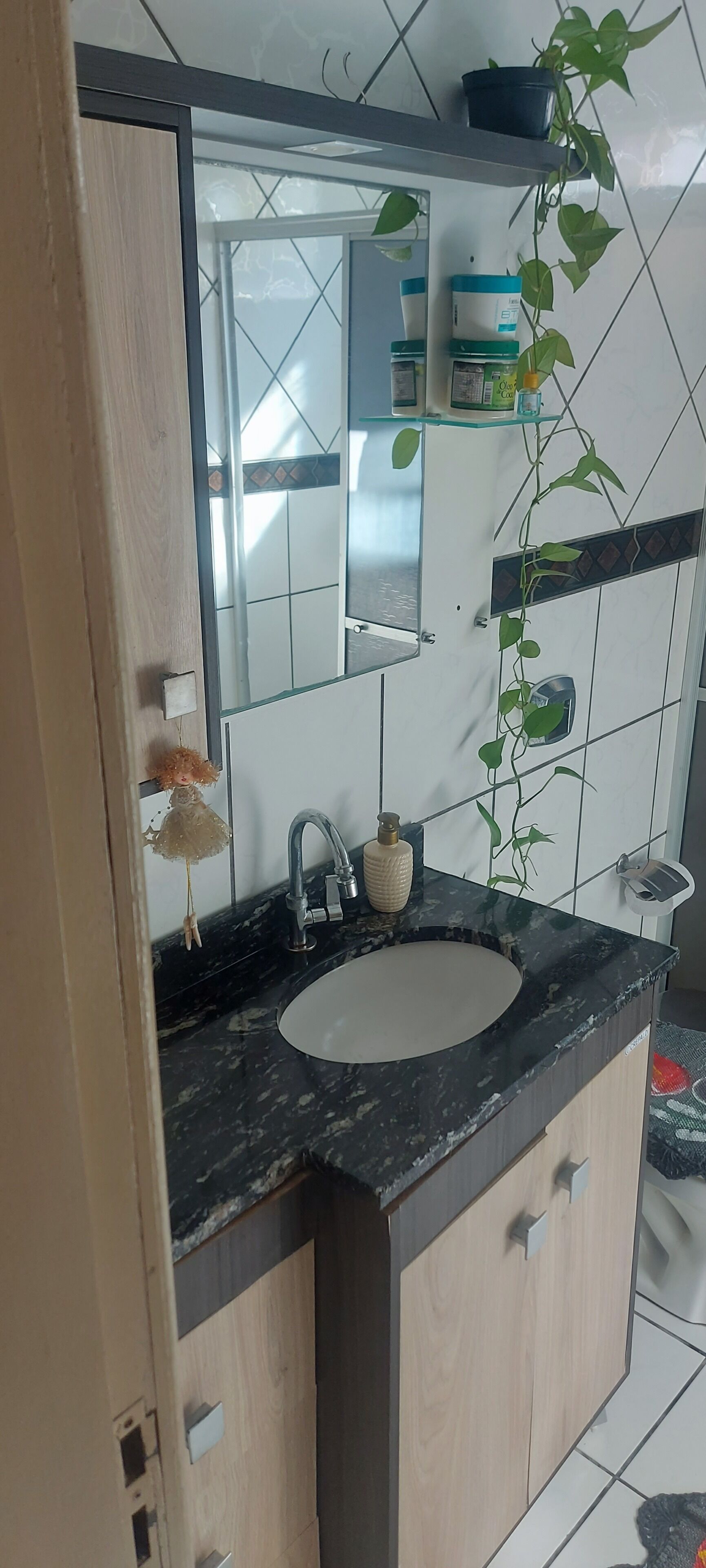 A bathroom with a sink, mirror, and a potted plant.