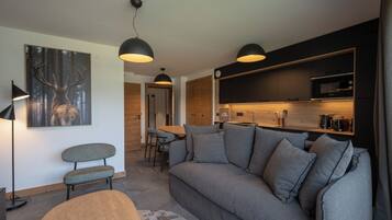 Una sala de estar moderna con un sofá gris, una mesa de centro de madera y un comedor con mesa y sillas de madera.