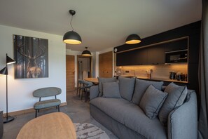 Un salon moderne avec un canapé gris, une table basse en bois et un coin repas comprenant une table et des chaises en bois.