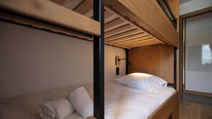 A bunk bed with a wooden frame and white bedding.