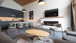 A modern living room with a fireplace, a television, and a dining area with chairs and a table.