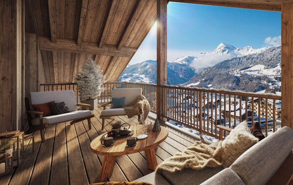 Une terrasse en bois avec une table ronde, deux canapés et un petit sapin de Noël.