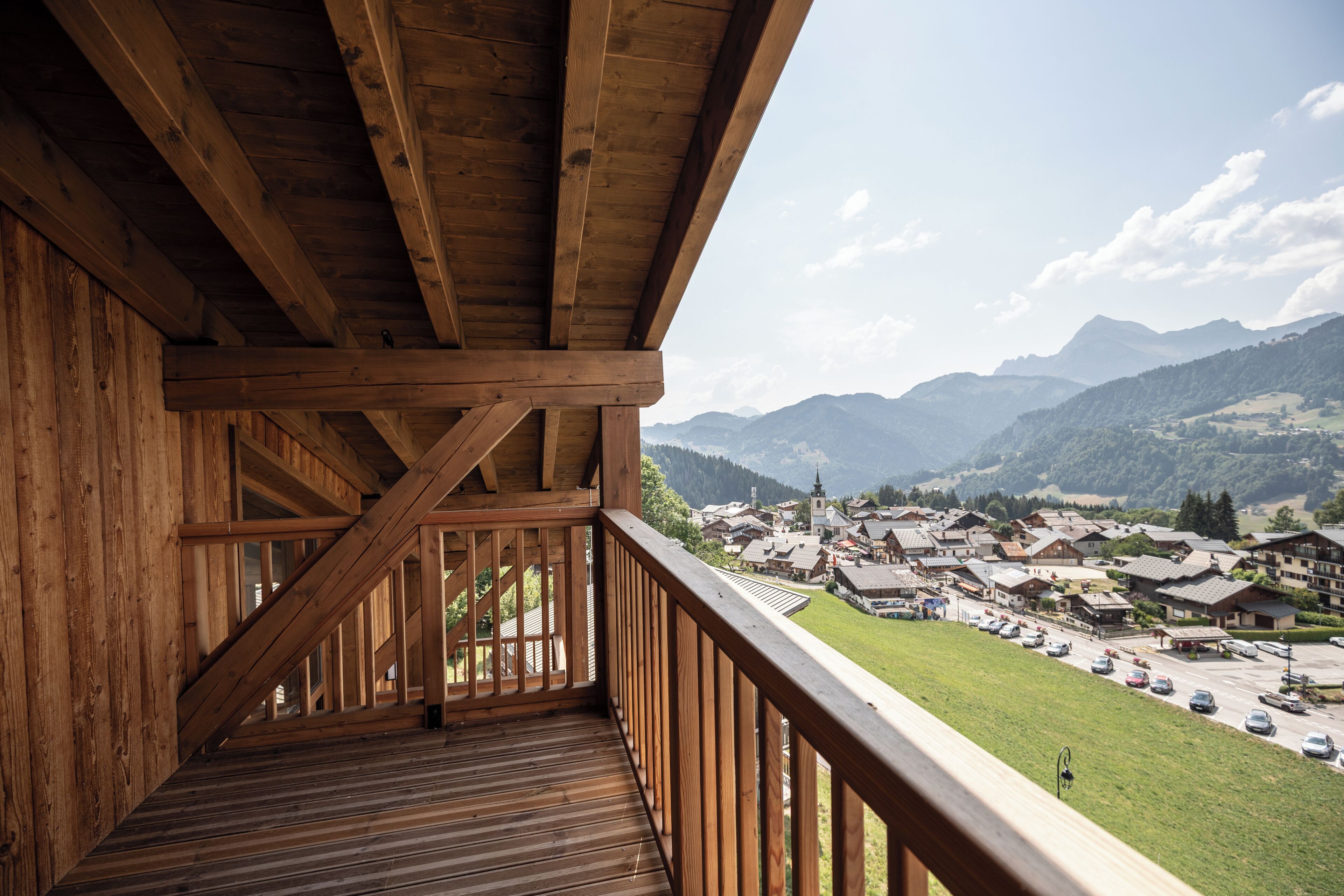 A wooden balcony with a view of a town and mountains.
