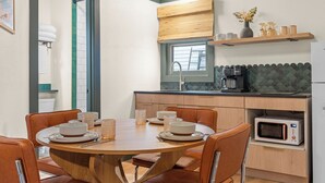 A compact kitchen with a dining table, chairs, a microwave, and a window. - The Drift Resort (Branson)