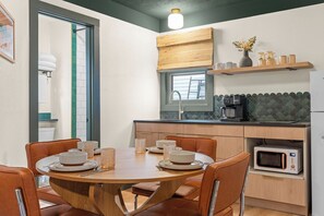 A compact kitchen with a dining table, chairs, a microwave, and a window. - The Drift Resort (Branson)