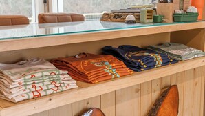 A wooden shelf with folded clothing, a glass table, and a window with a view of trees. - The Drift Resort (Branson)