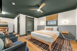 A bedroom with a bed, a ceiling fan, a nightstand, a window, and a built-in wardrobe. - The Drift Resort (Branson)
