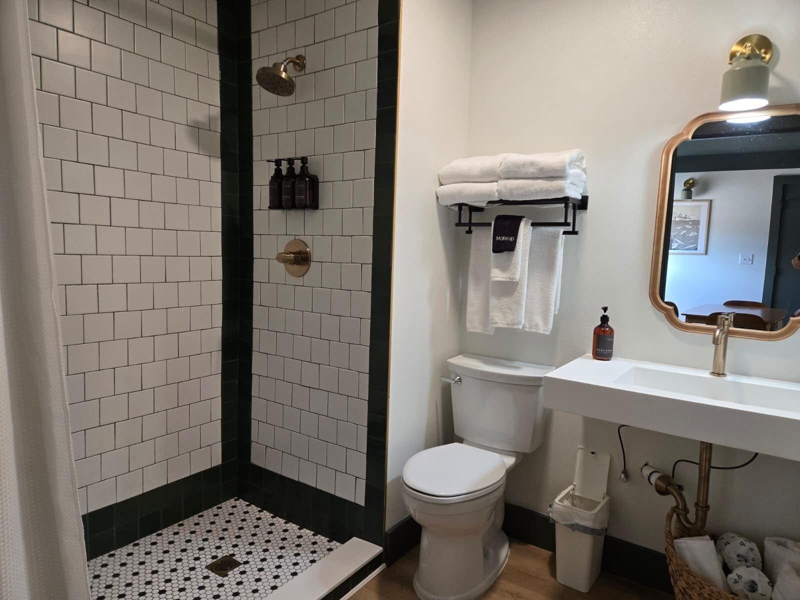 A bathroom with a shower, toilet, sink, and a mirror.