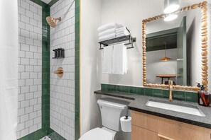 A bathroom with a shower, toilet, sink, and a mirror with a wooden frame. - The Drift Resort (Branson)