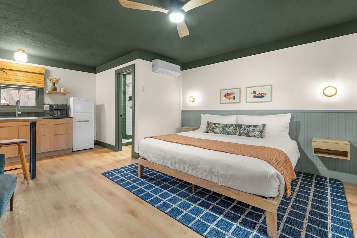 A bedroom with a bed, bedside table, and a window.