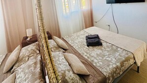 A hotel room with a bed, a ceiling fan, a TV, and a window with curtains.